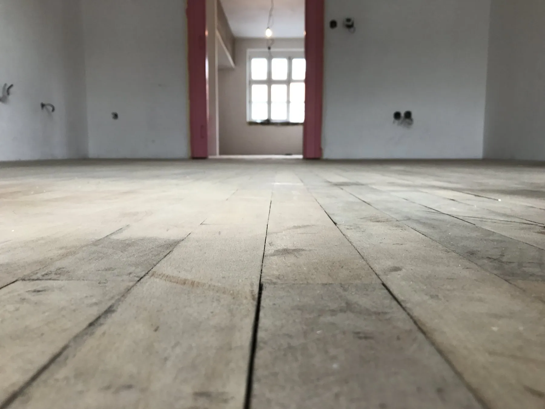 Podlaha po prvním broušení, pohled nízko nad zemí směrem k oknu
